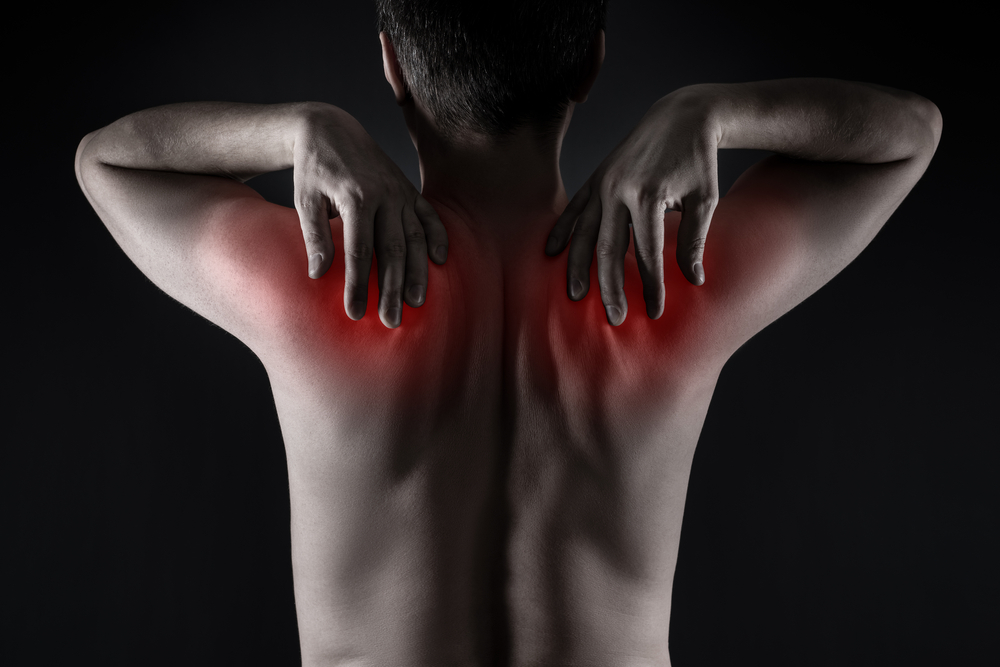 Man holding his neck and upper back due to cervical spine pain. Man holding his neck and upper back due to cervical spine pain.